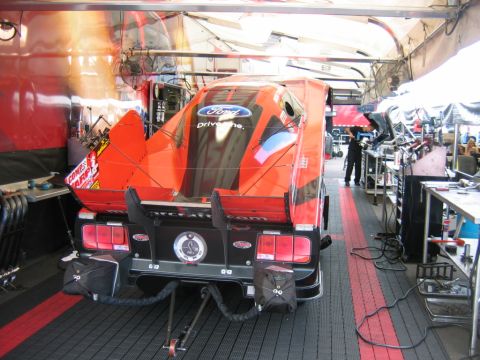1992 Ford Mustang - Rear view of a 1992 Ford Mustang drag car in a pit garage, Ford branding and racing livery.