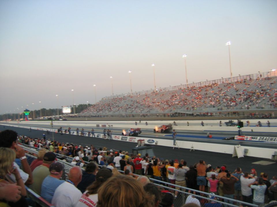 Spectators watch drag racing from stadium seating at a drag strip