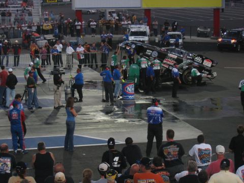 1992 Ford Mustang - A drag racing car is being serviced by its crew at an NHRA event, with spectators in the foreground.