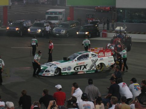 1992 Ford Mustang - A drag racing car with a 'GTX' livery is being attended to by its crew on a race track.