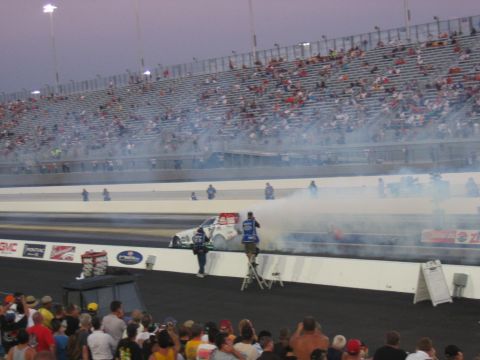 1992 Ford Mustang - A drag racing car creates a large smoke cloud during a burnout event at a race track.