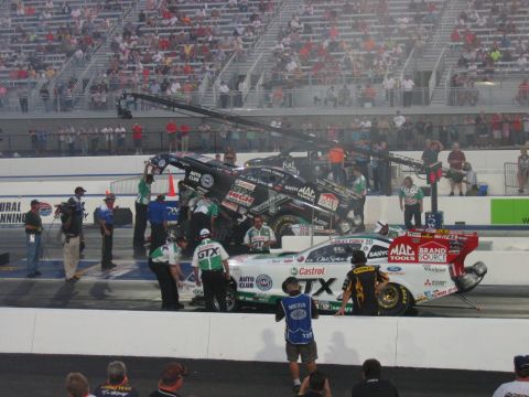 1992 Ford Mustang - Drag racing cars and crews on the track at an event with spectators in the stands.