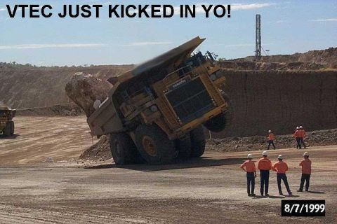 2000 Mercury Grand Marquis - Mining dump truck tilted with a large rock in its bed, several workers nearby.