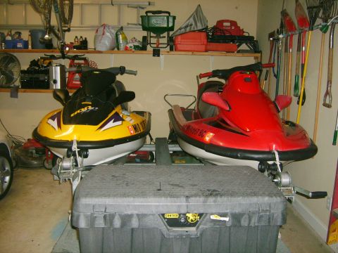 1994 Ford Bronco - Two jet skis are stored in a garage, with various tools and equipment visible on shelves and walls.
