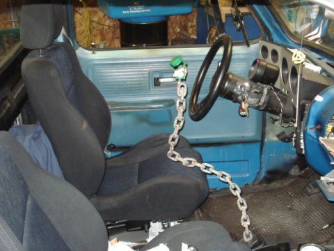 1979 Chevrolet C/K Pickup - The interior of a blue pickup truck shows aftermarket seats and a chain secured to the steering wheel.