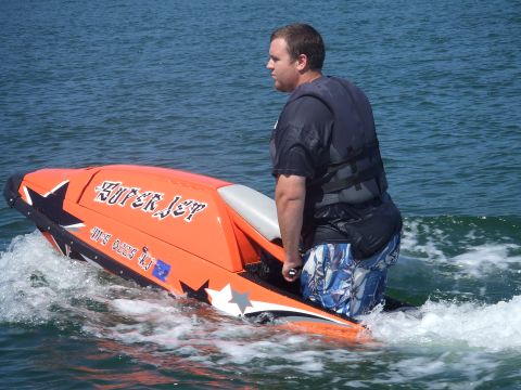 1995 Ford Mustang - A person rides an orange jet ski labeled 'SUPER JET' through the water.