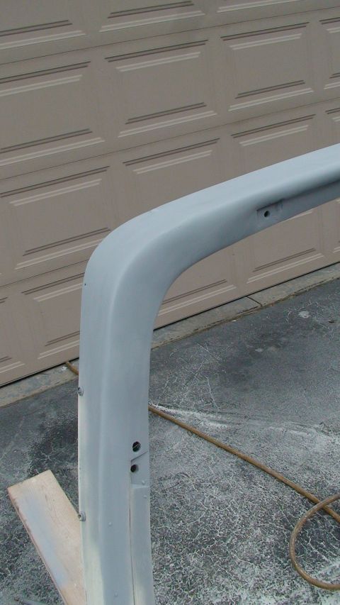 1979 Ford Bronco - A section of a vehicle's roll bar, prepped for paint, sits in front of a garage door.