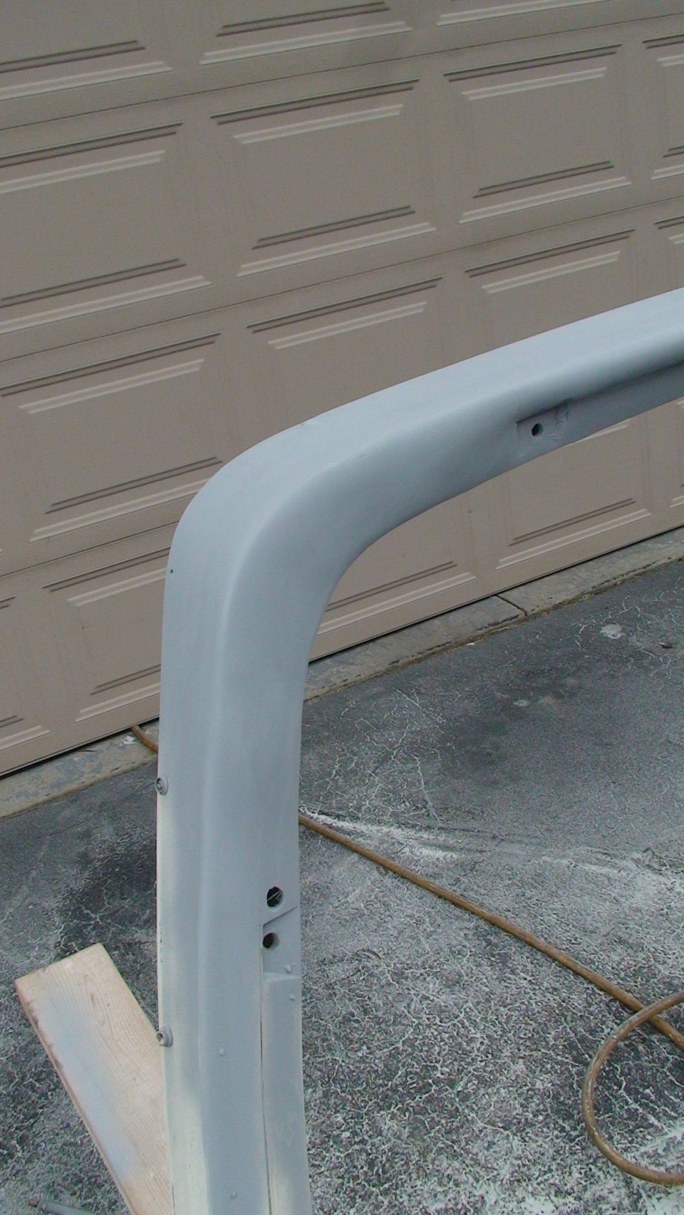 gray roll bar section with mounting holes, in front of garage door