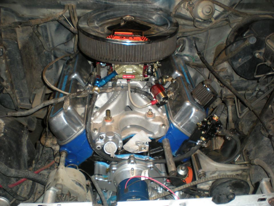 Engine bay with chrome air cleaner, V8 engine, blue valve covers, and fuel system components