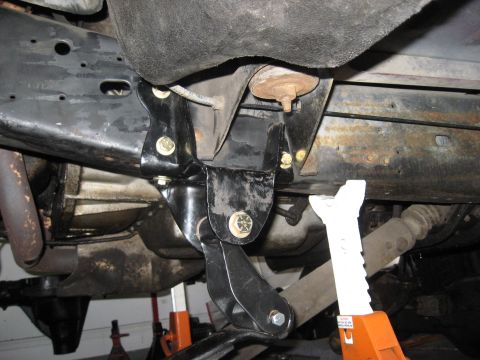 1991 Ford Bronco - Close-up view of aftermarket suspension components and supporting jack stands underneath a vehicle.