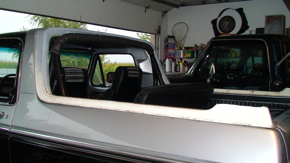 Silver and black 1978 Ford Bronco interior and side profile, parked in a garage next to another vehicle