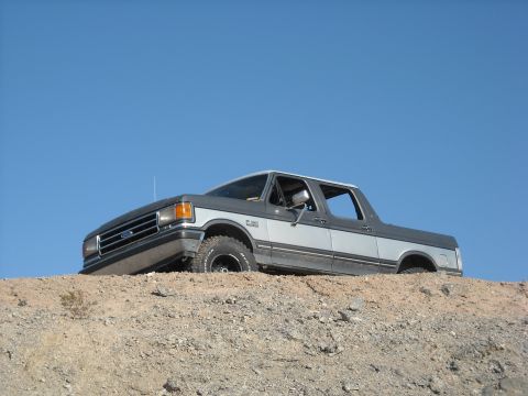 1990 Ford C-150 (Centurion Conversions) - Two-tone 1990 Ford C-150 (Centurion Conversions) parked on a dirt incline under a clear blue sky.