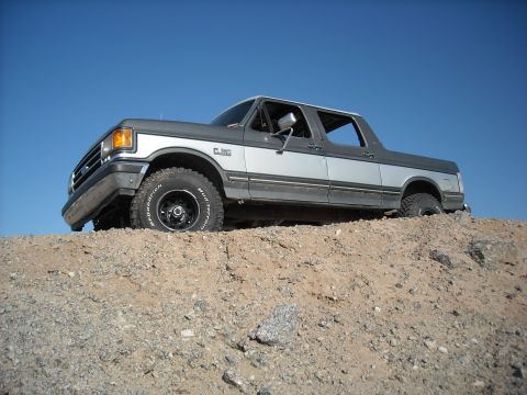 1990 Ford C-150 (Centurion Conversions) - This two-tone Ford F-Series truck is positioned on a dirt mound against a clear blue sky.