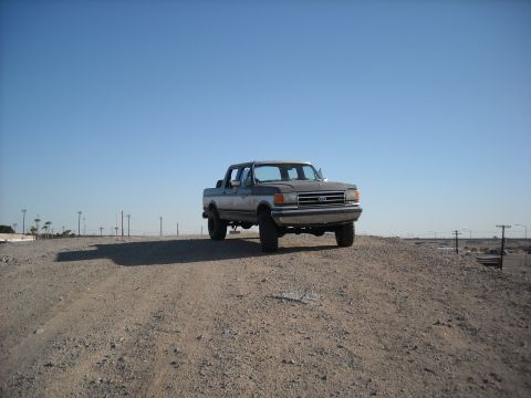 1990 Ford C-150 (Centurion Conversions) - This 1990 Ford C-150 Centurion Conversions truck is seen from a three-quarter front view on a dirt mound under a clear blue sky.
