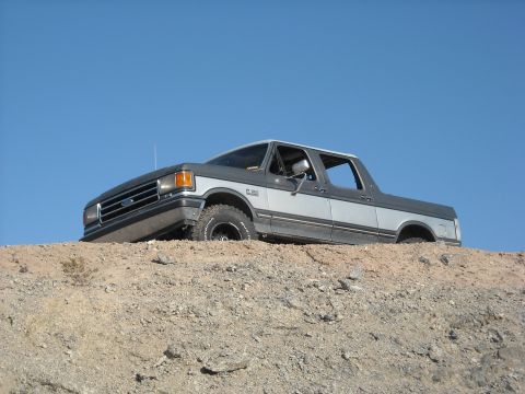 1990 Ford C-150 (Centurion Conversions) - Ford Bronco navigating rough terrain against a bright blue sky.