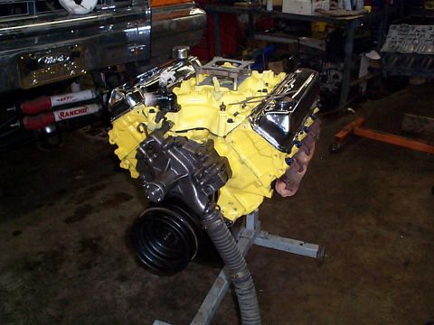 1978 Ford Bronco - Engine rebuild project a yellow V8 engine with chrome valve covers, mounted on a stand.