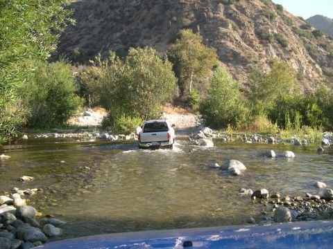 2007 Toyota FJ Cruiser - A white pickup truck navigates a rocky riverbed under a clear sky.