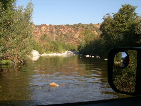 2007 Toyota FJ Cruiser - View of a river crossing from the driver's perspective, with the side mirror showing the surrounding vegetation.