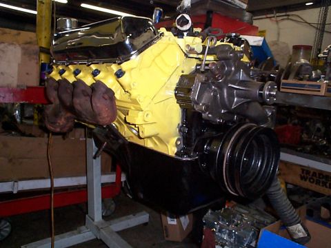 1978 Ford Bronco - A V8 engine, painted yellow with chrome accents, is mounted on an engine stand in a workshop.