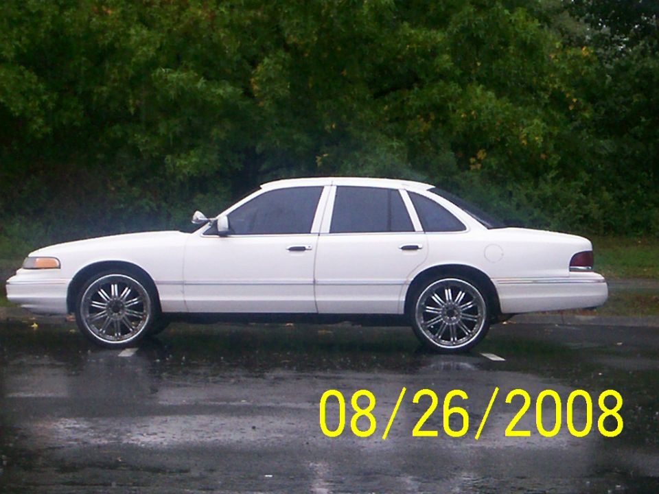 Side profile of a white Crown Victoria sedan on chrome wheels