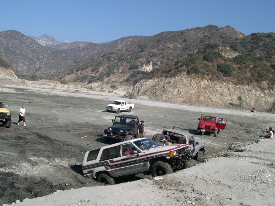 Silver first-gen Toyota 4Runner in a mud pit with Jeeps behind at a canyon off-road park