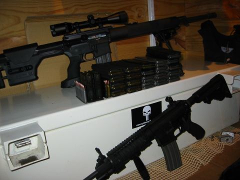 1996 Ford Bronco - Two black rifles are displayed on a white surface with stacks of ammunition magazines. A large rifle with a scope is in the background, and…