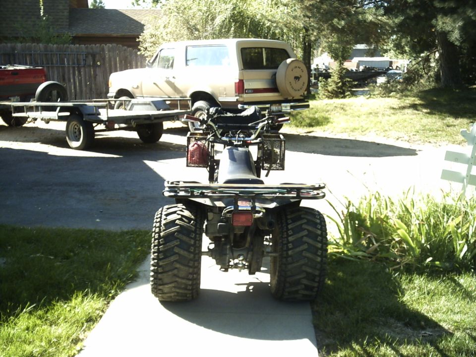 Rear view of ATV on walkway with tan SUV and trailer behind