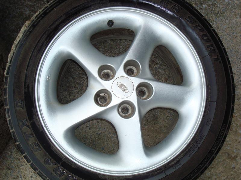 Silver 5-spoke alloy wheel with Ford logo on a tire.