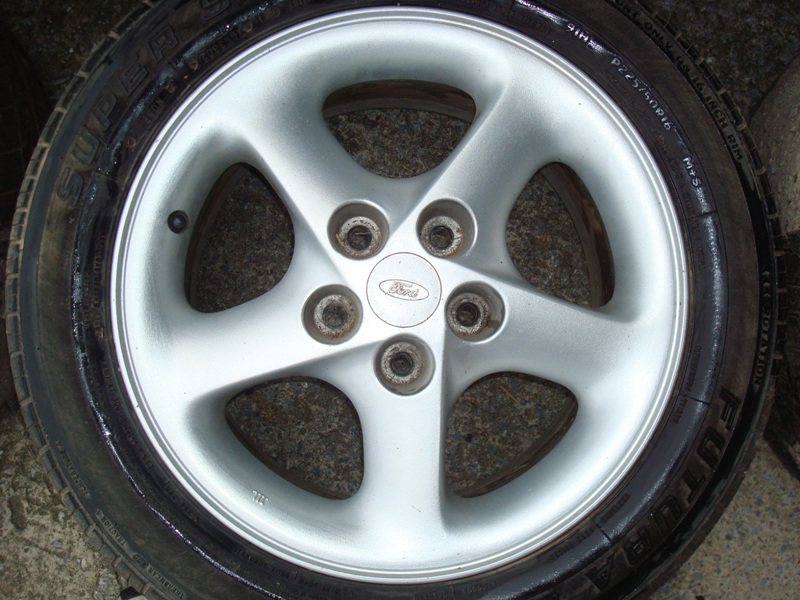 Silver 5-spoke alloy wheel with Ford logo on a tire.