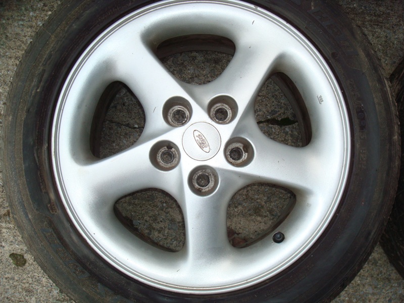 Silver five-spoke Ford alloy wheel on a tire.