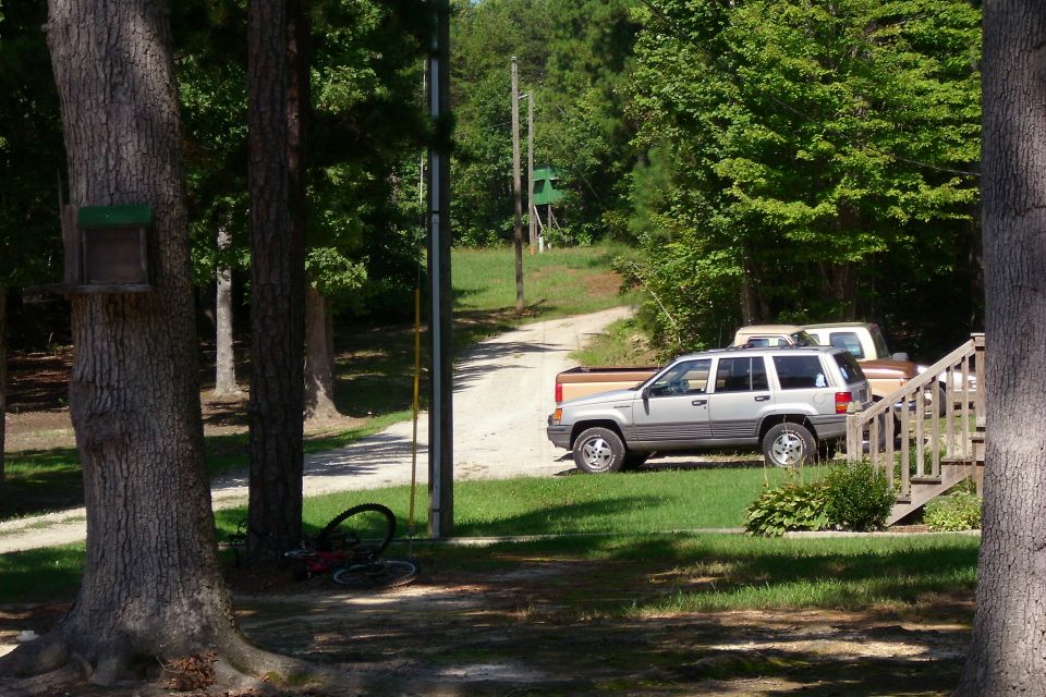 Silver Jeep Grand Cherokee and pickup parked in a wooded driveway