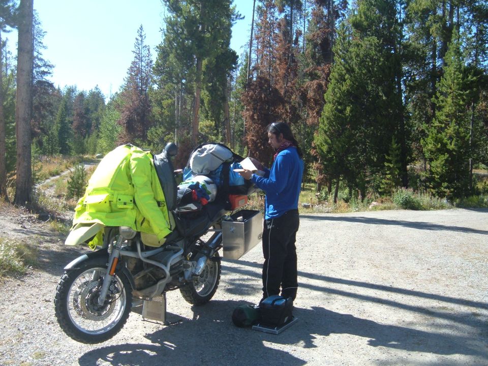 Motorcycle loaded with camping gear, a person consults a map
