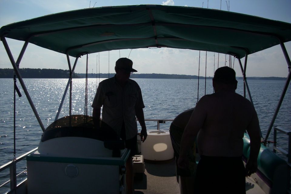 Two silhouetted men under a pontoon boat canopy on a sunlit lake