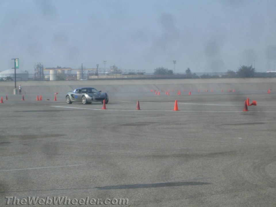 Silver sports coupe running an autocross course marked with orange cones on a paved lot