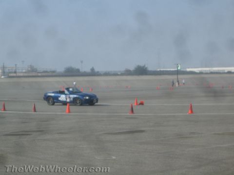 1985 Ford Mustang - A blue convertible sports car with the number 522 on its door is driving on a race track marked with orange cones. The car appears to be a…