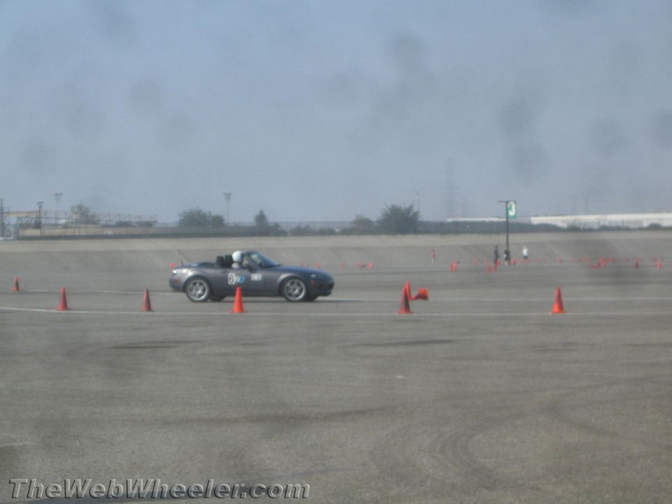 Gray convertible sports car with racing number B50 driving on a cone-marked course.