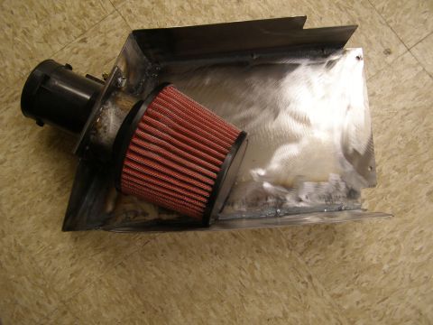 2003 Ford Crown Victoria - A custom metal fabricated air intake box with a red cone air filter and black plastic intake tube is shown resting on a linoleum floor.
