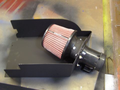 2003 Ford Crown Victoria - A black metal air intake box is shown with a red K&N air filter and black plastic intake tube attached. The parts are laid out on a speckle…
