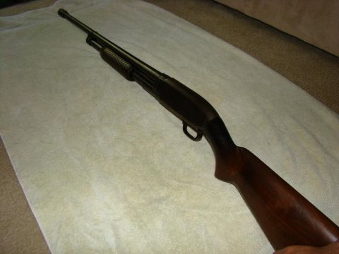 1989 Ford Bronco - A close-up, high-angle shot shows a dark-colored pump-action shotgun with a wooden stock and forend resting on a white towel.