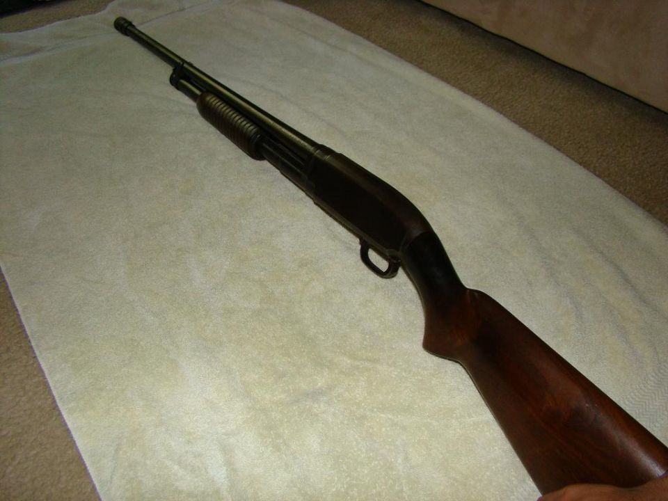 Pump-action shotgun with wooden stock on a white towel.