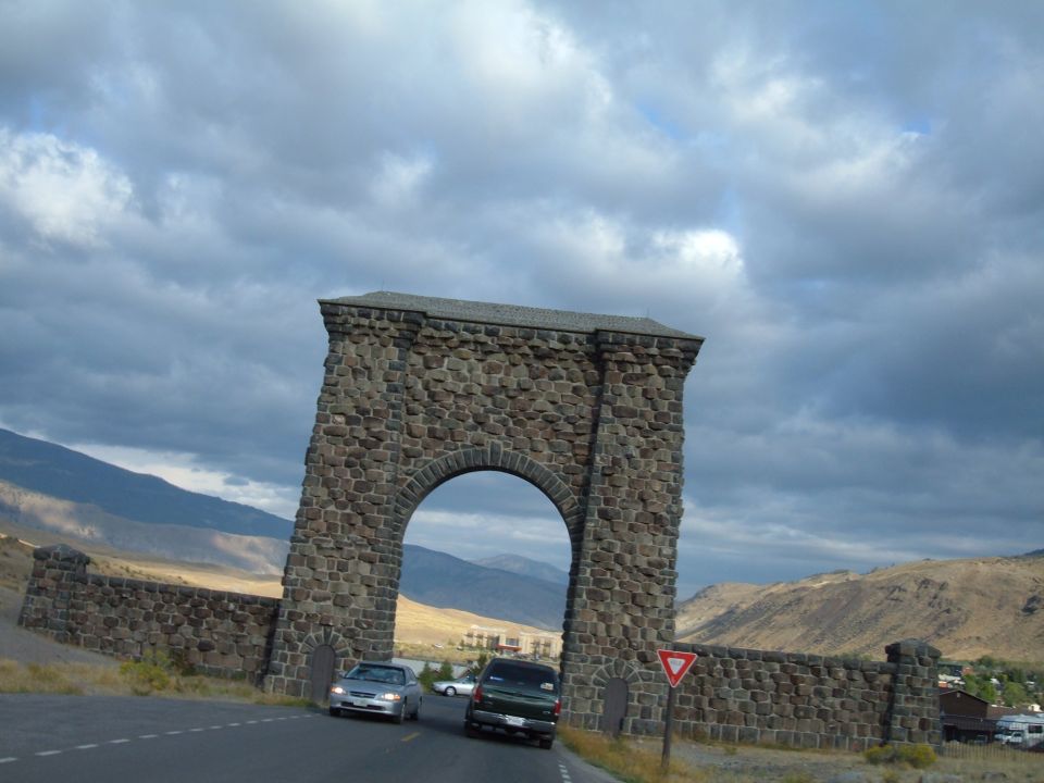 Stone archway over a road with cars passing under it.