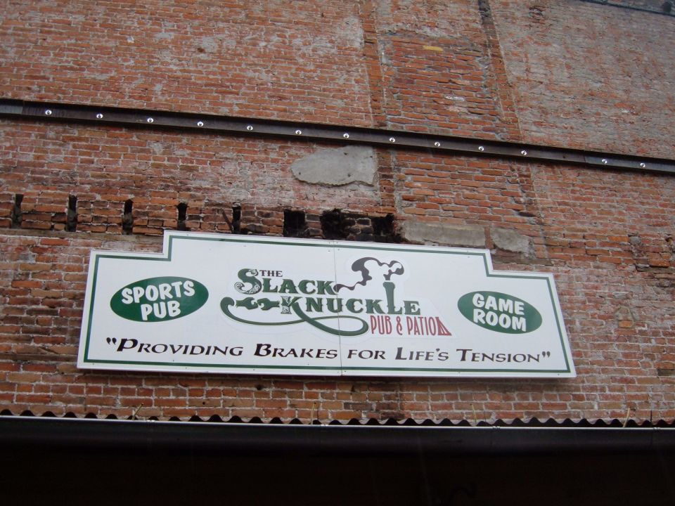 Sign for The Black Knuckle Pub & Patio on a brick wall.