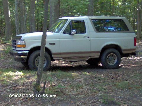 1995 Ford Bronco - White 1995 Ford Bronco parked off-road in a wooded area.