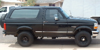 1994 Ford Bronco - Side view of a black 1994 Ford Bronco SUV with a spare tire mounted on the rear door.