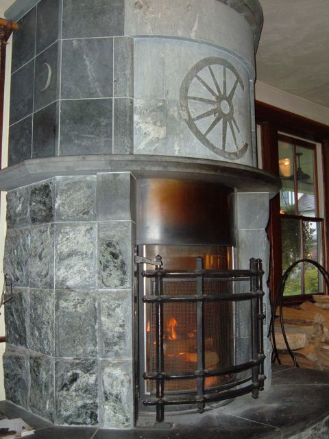 1998 BMW R1100GS ABS - A stone fireplace features a decorative wagon wheel motif and a metal grate in front of the firebox.
