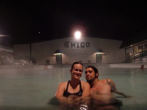 1998 BMW R1100GS ABS - A couple enjoys a nighttime soak in a steamy hot spring, with a building illuminated behind them.
