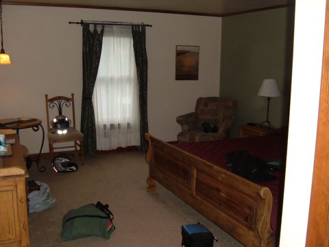 1998 BMW R1100GS ABS - A motorcycle helmet rests on a chair in a room with a bed and armchair.