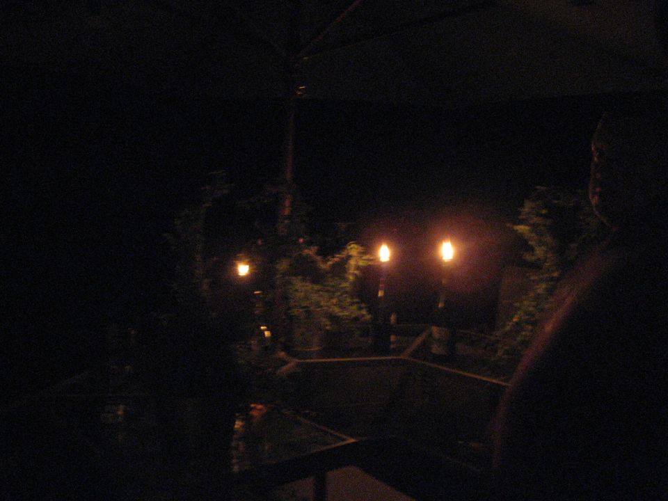 Dark night photo of a backyard patio lit by tiki torches