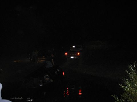 1995 Ford Bronco - Vehicles are stuck in dark water at night, with only taillights visible.