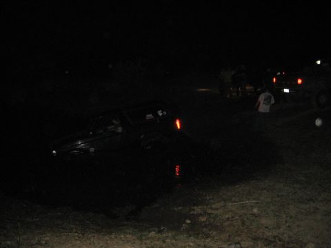 1995 Ford Bronco - A vehicle is stuck in the water at night, with other vehicles and people around.